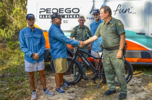 Coker Day (left) shakes hands with SCDNR’s Major Gary Sullivan after delivering the Pedego bike.