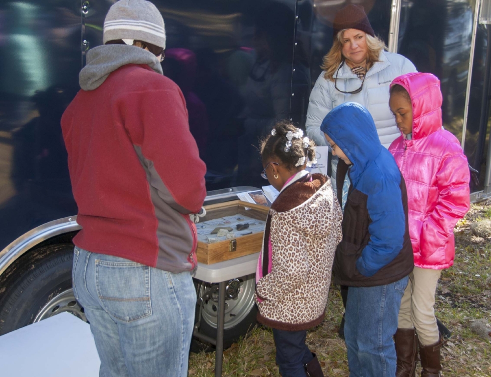 A group of schoolchildren attending one of the "public day" events held during the excavation marvel at some of the artifacts discovered at Fort Frederick and the surrounding area, home to "Smith's Plantation" during the 1800s.