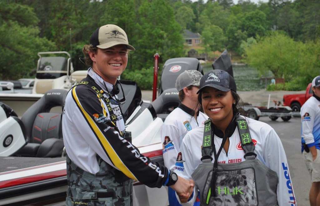 A young man (Andrew Snelgrove) and young woman (Anastasia Patterson) shaking hands at a fishing tournament.