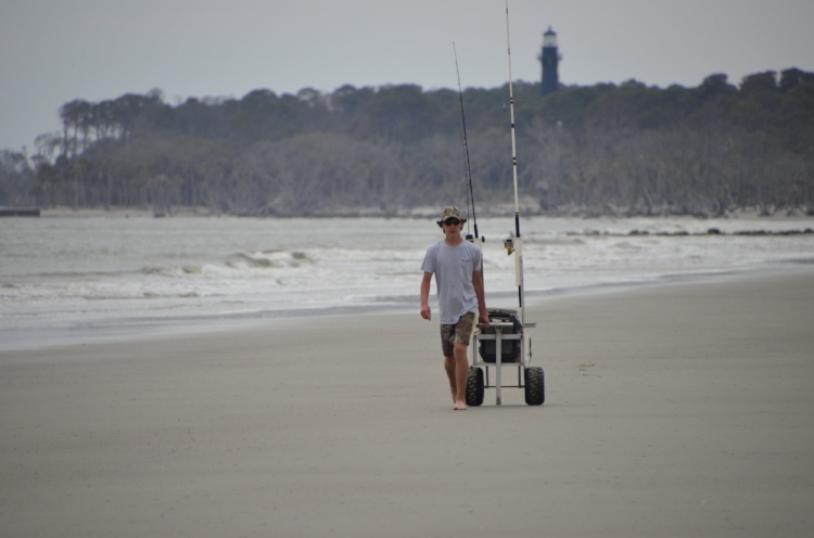 Above: A teenager pulls his well-stocked surf-fishing cart towards the northern tip of Hunting Island State Park, where the Harbor River meets the ocean. Below (clockwise from upper left): A vacationing teen tries his luck at Hunting Island; &n…