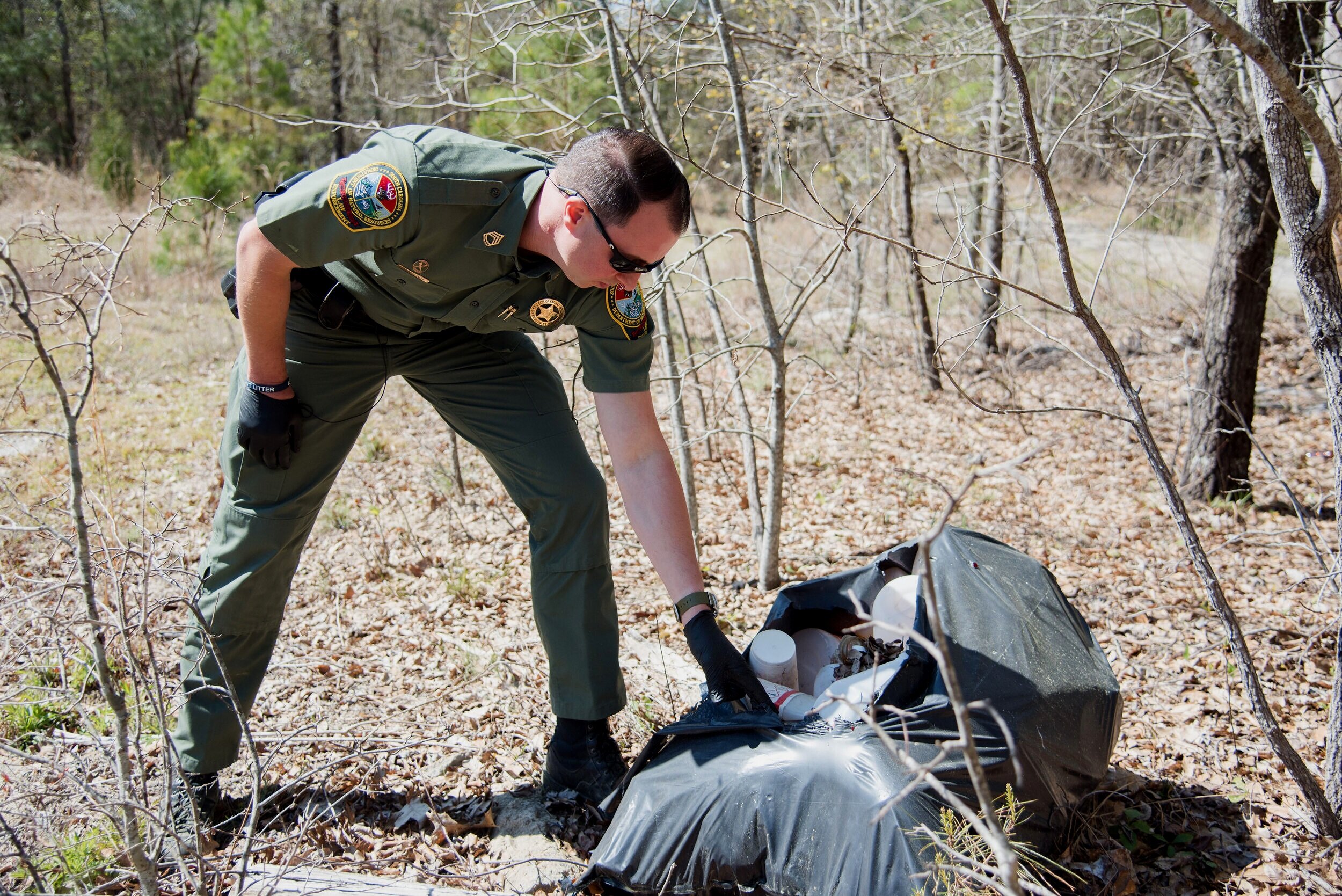 An SCDNR Conservation Officer investigates illegal dumping in a remote area. SCDNR Officers routinely find and investigate illegal dumpsites while on patrol, as well as assisting county and local litter control agencies with illegal dumping investig…