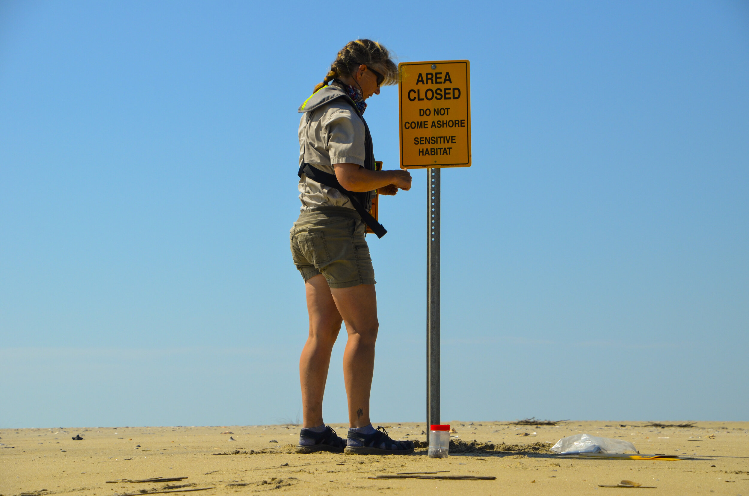 Shorebird Steward Jennifer Cahill places a sign on an island within the Cape Romain National Wildlife Refuge.. [SCDNR photo by David Lucas]