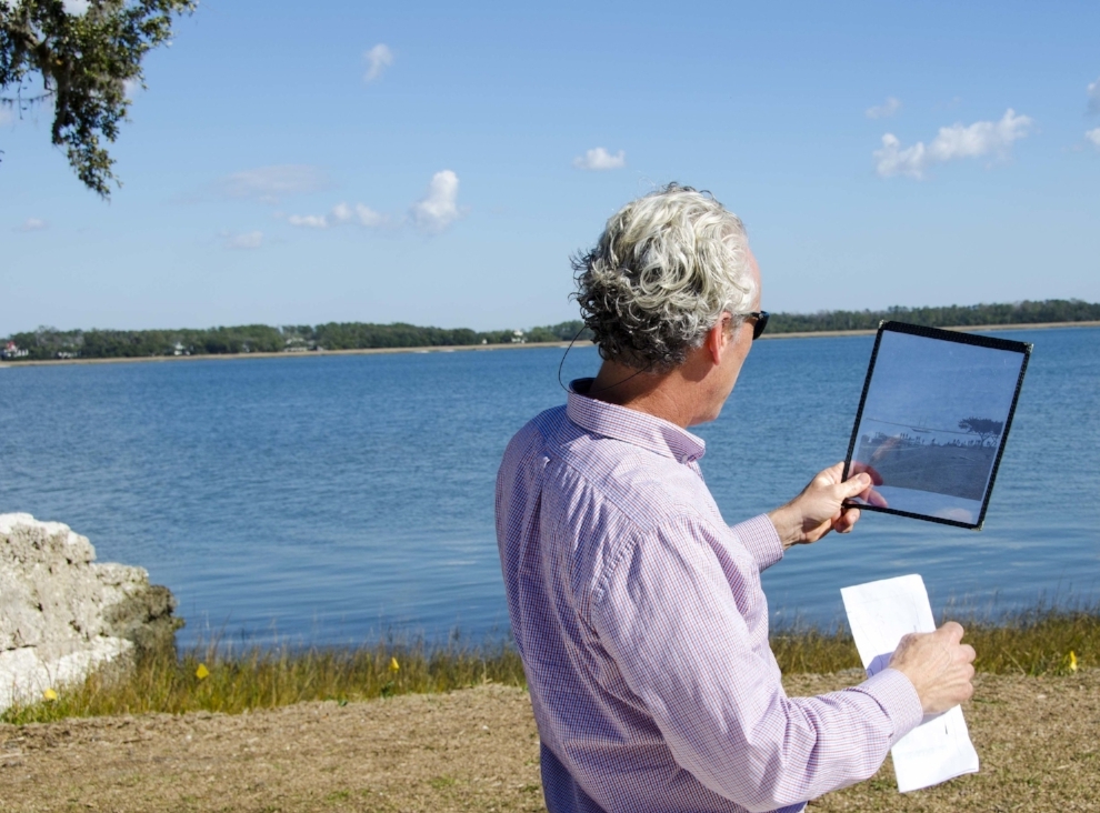 SCDNR Heritage Trust program archaeologist Sean Taylor studies a transparency of a photo taken during the 1800s of a schooner moored in the river, when the fort's walls were used as supports for a dock, attempting to ascertain the camera operator's …